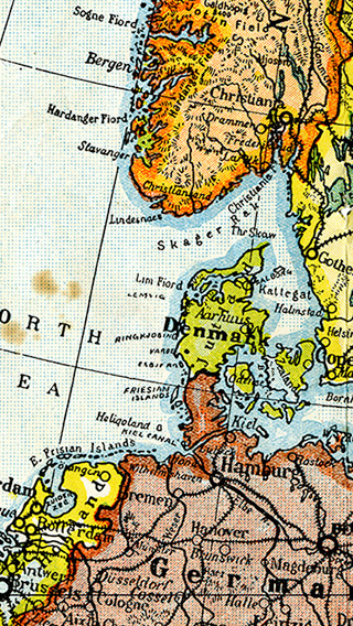 Image is a coloured and edited section of a war map from 1914 which depicts Cape Breton Island in a highlighted circle. Several European countries are featured in the image, including the Ireland, Scotland, England, Holland, France, Germany, Denmark, Norway, and Sweden.
