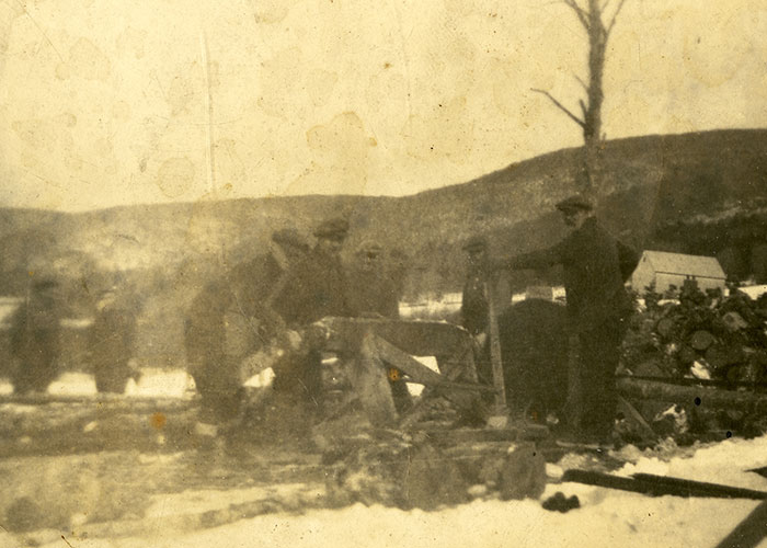 Sepia photograph of men working in the rural countryside during the winter cutting wood.